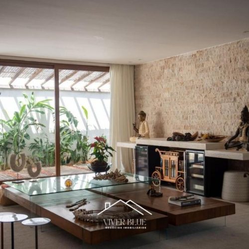 Sala de estar com parede em pedra, decoração sofisticada e ambiente integrado.