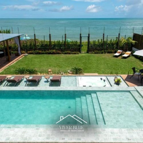 Área externa com piscina, jardim e vista para o mar, proporcionando lazer e contato com a natureza.